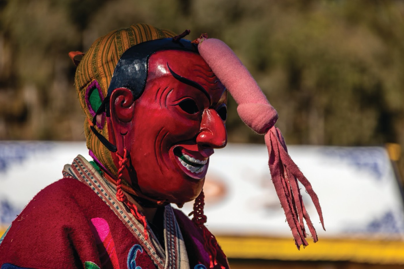 An atsara in a red mask and ragged costume at a Bhutanese tshechu festival