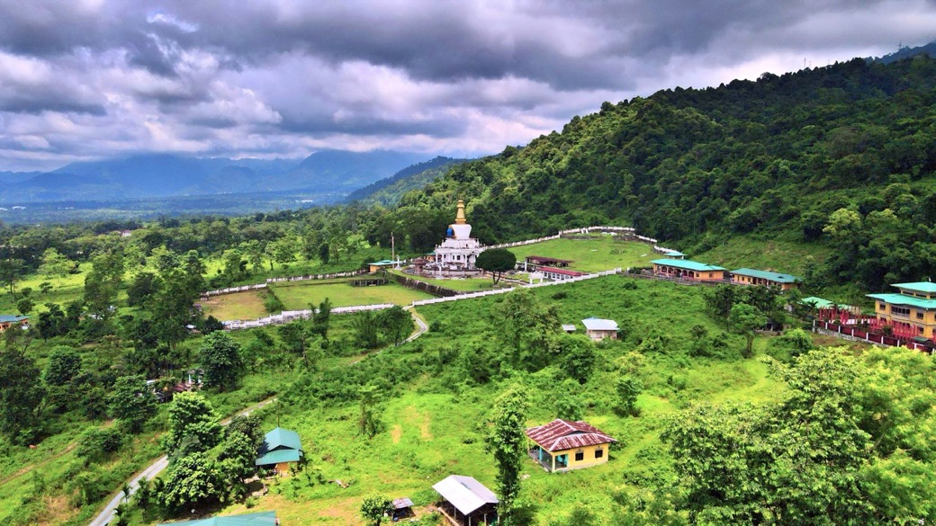 A hilltop chorten with prayer flags overlooking the Gelephu valley